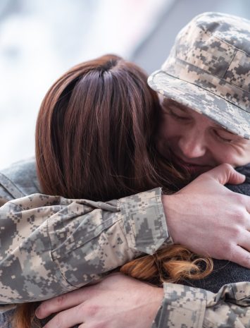 Man hugging his wife after returning home from service A handsome man dressed in a military uniform passionately hugs his partner as he greets her returning from his military service in this close-up.